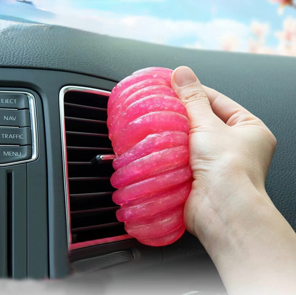 Pink car cleaning gel pressed into a car air vent to lift dust