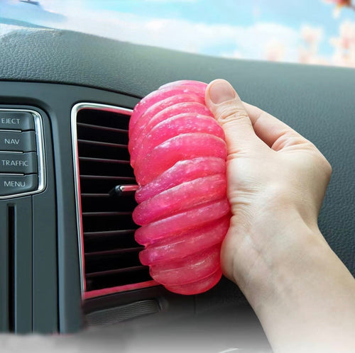 Pink car cleaning gel pressed into a car air vent to lift dust