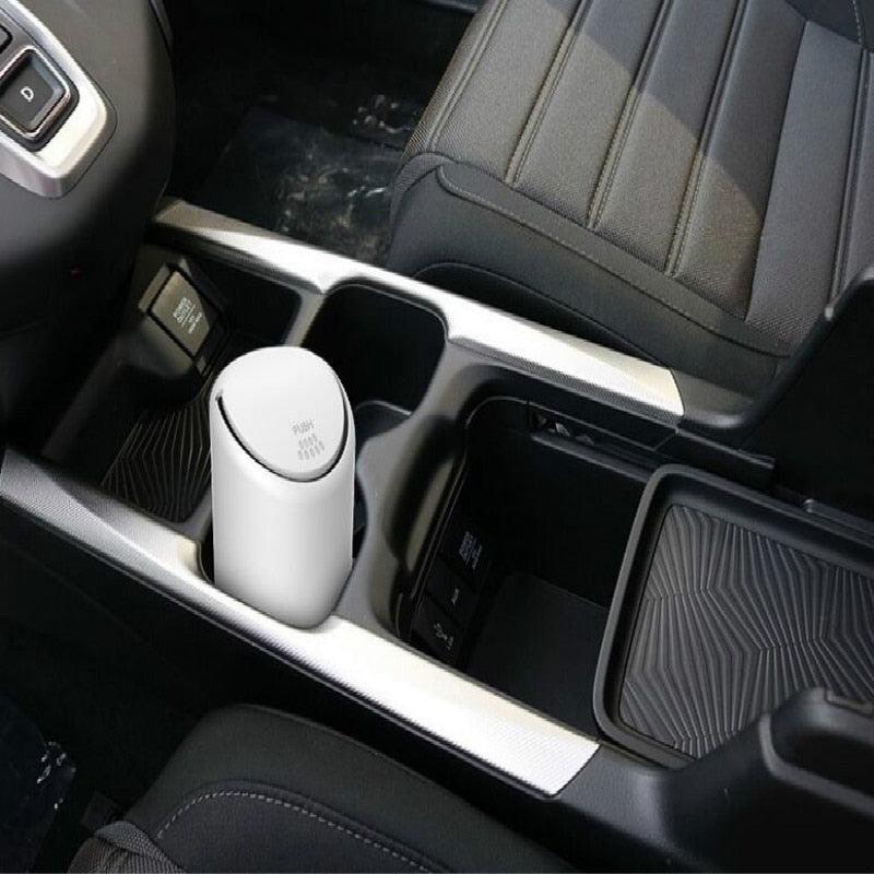 White mini trash can placed in a car center console cup holder